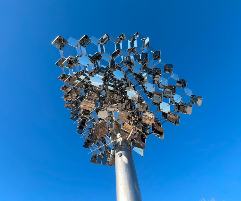 Completed metal fine-art sculpture erected at its final destination with a blue sky behind it