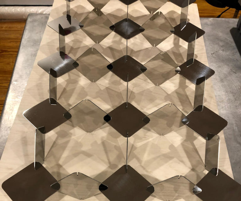 Transparent and brown square pieces linked together in a sculpture on a table.