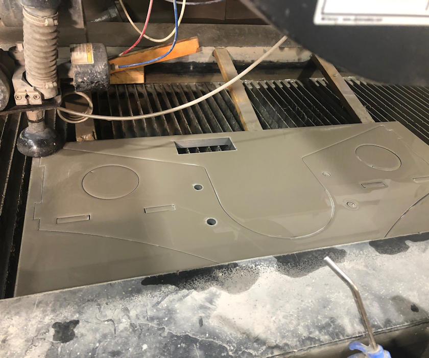 Waterjet Cutter with metal sheet that has been cut on the bench