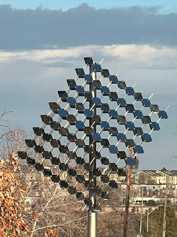 The Pneuhaus metal sculpture with clouds, trees and buildings in the background.